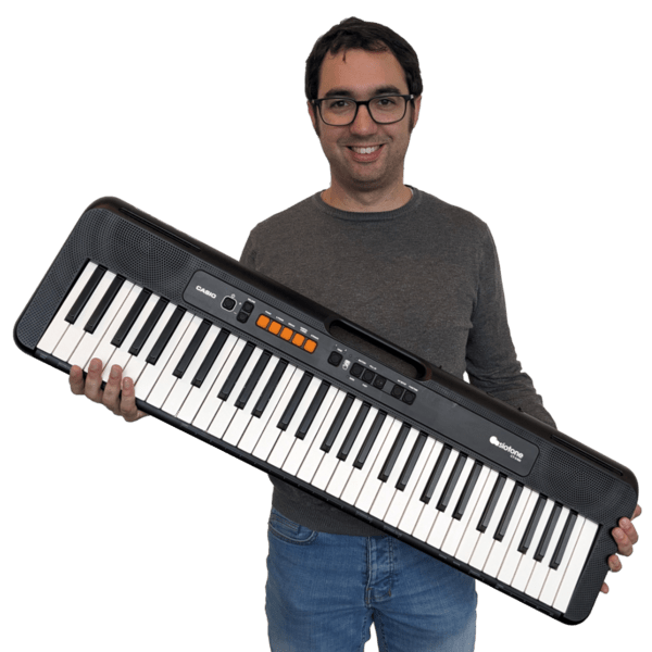 Smiling man with glasses holds a casio keyboard, advertising pianoles Den Haag